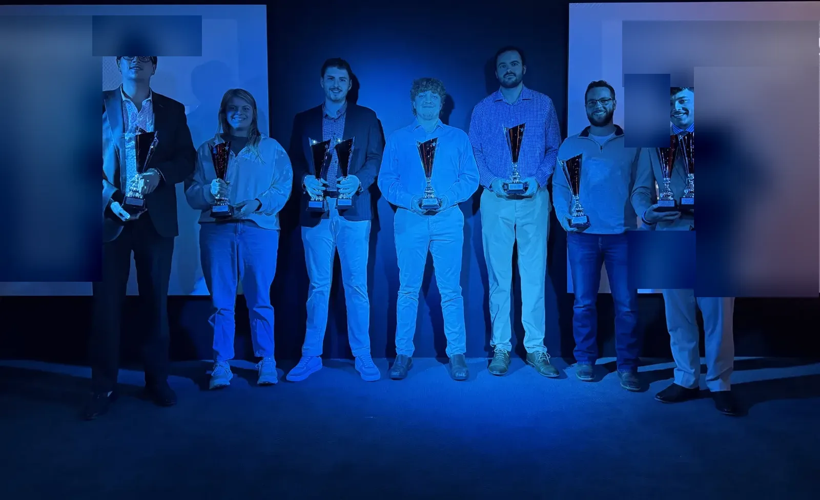 Team members on stage holding awards at a company recognition night